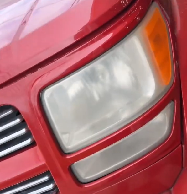 Oxidized headlight before restoration on a red truck