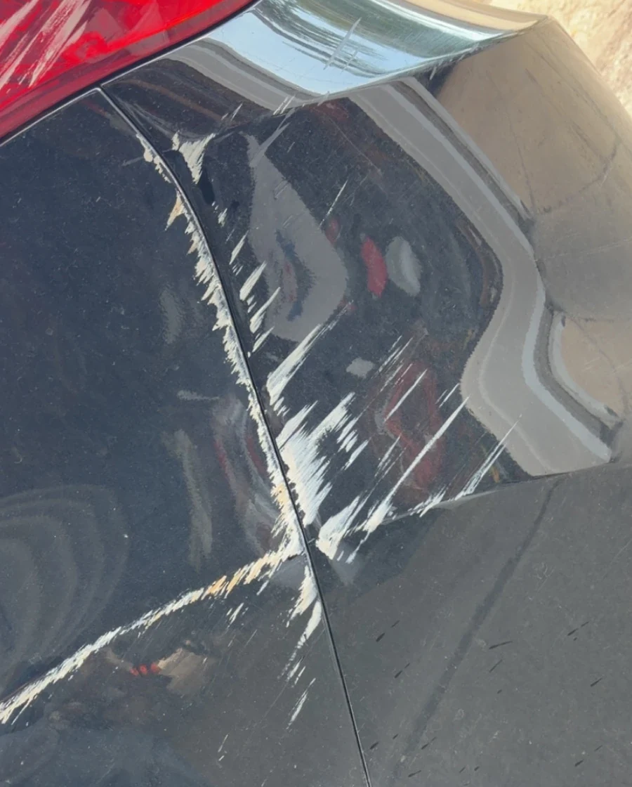 Rear quarter panel with heavy white scuff marks before cleanup